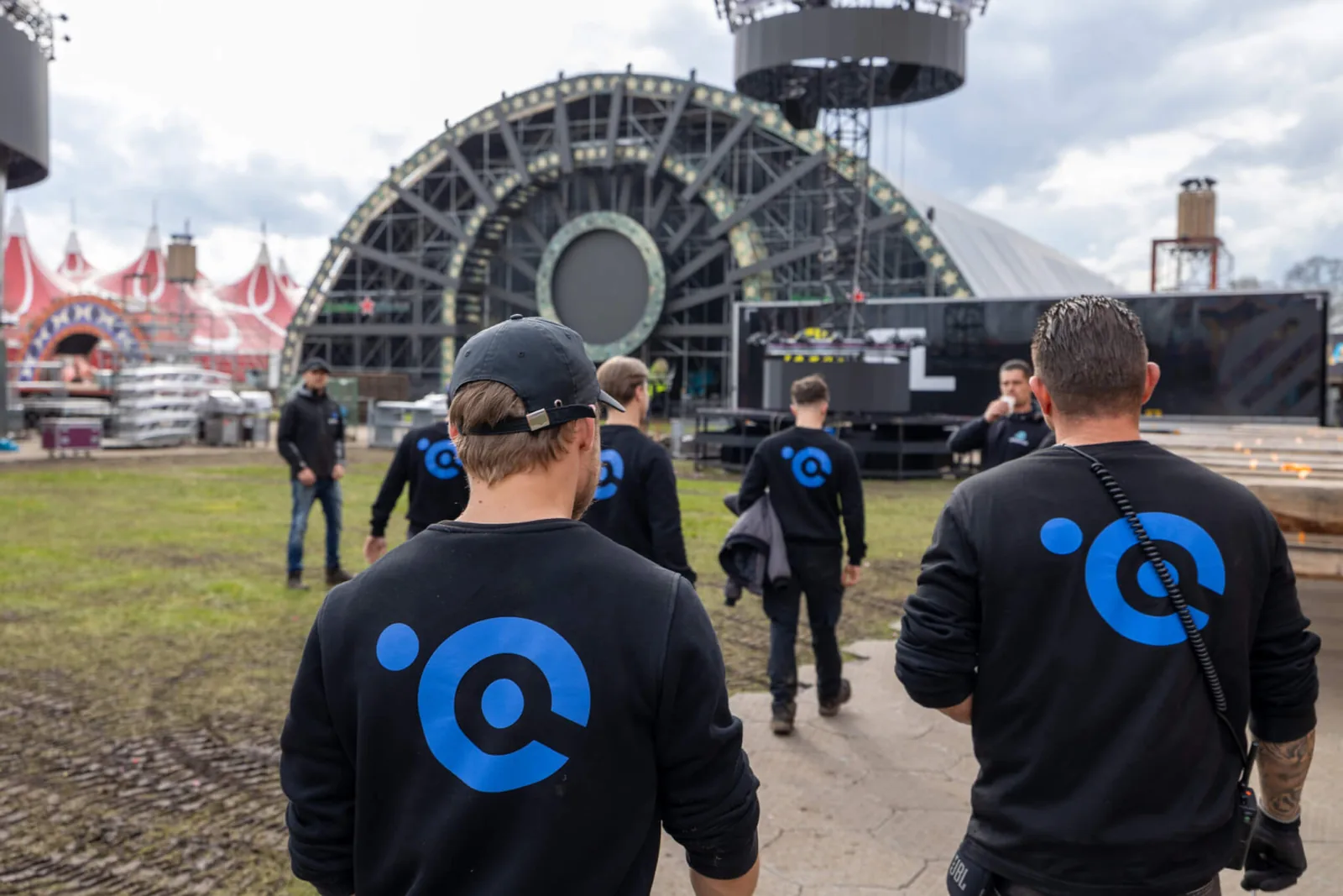 Crew van Crew-4You loopt over het festivalterrein naar het podium tijdens de opbouw